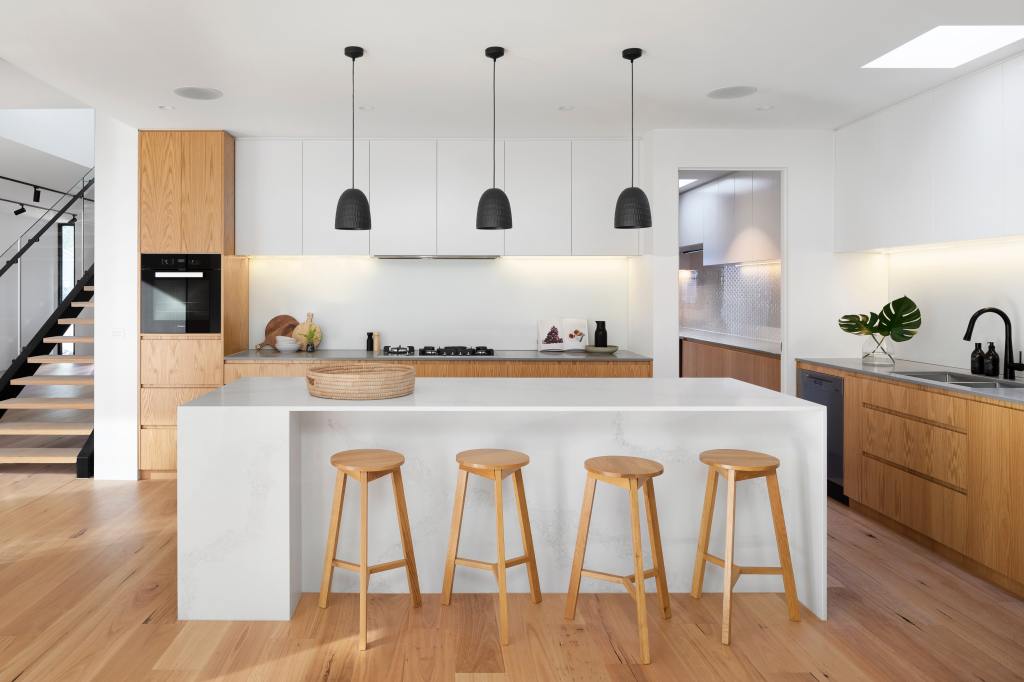 This is an image of a modern style kitchen with white and natural wood furnishings. 
  